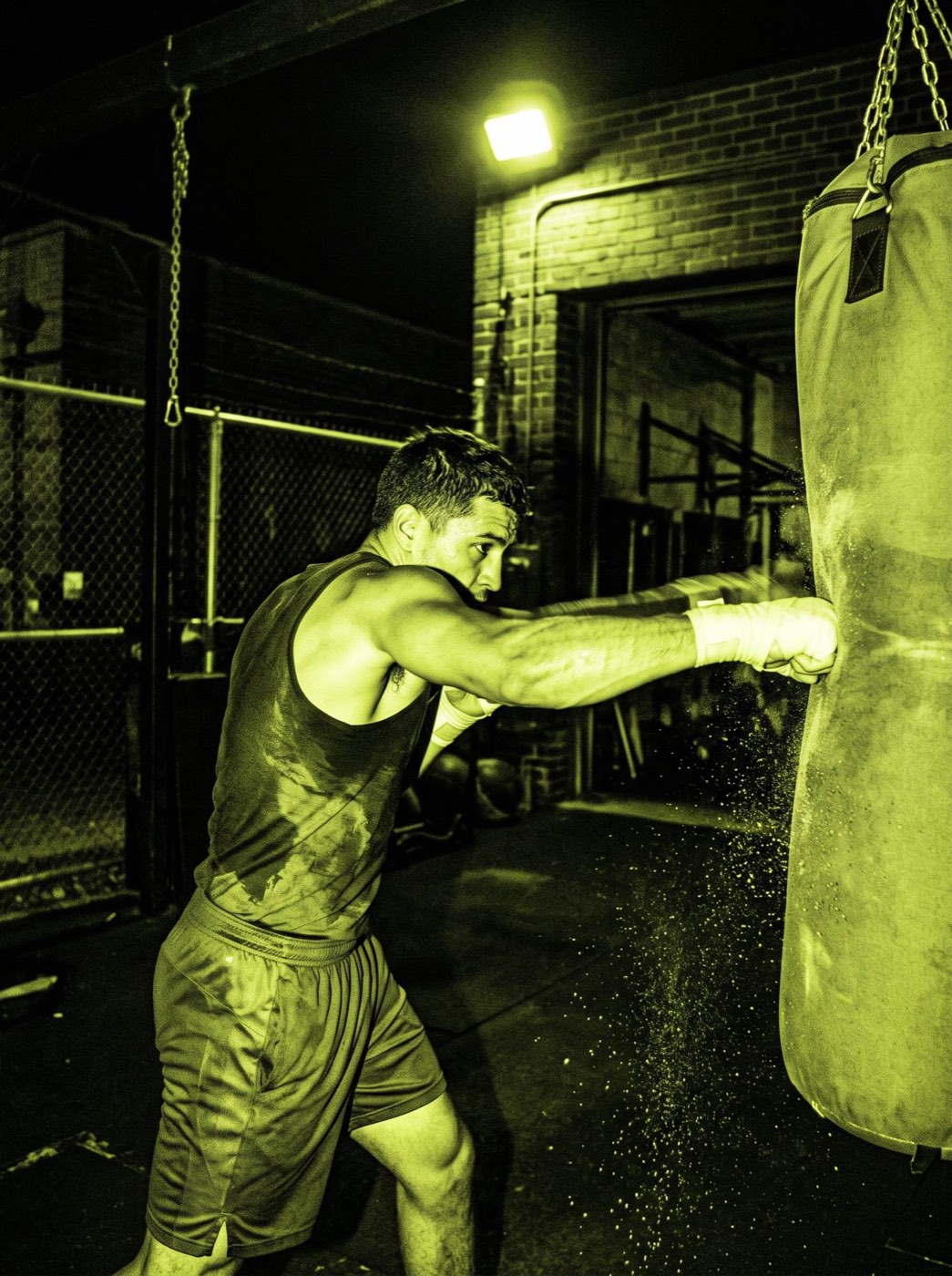 A boxer hitting a heavy bag at night