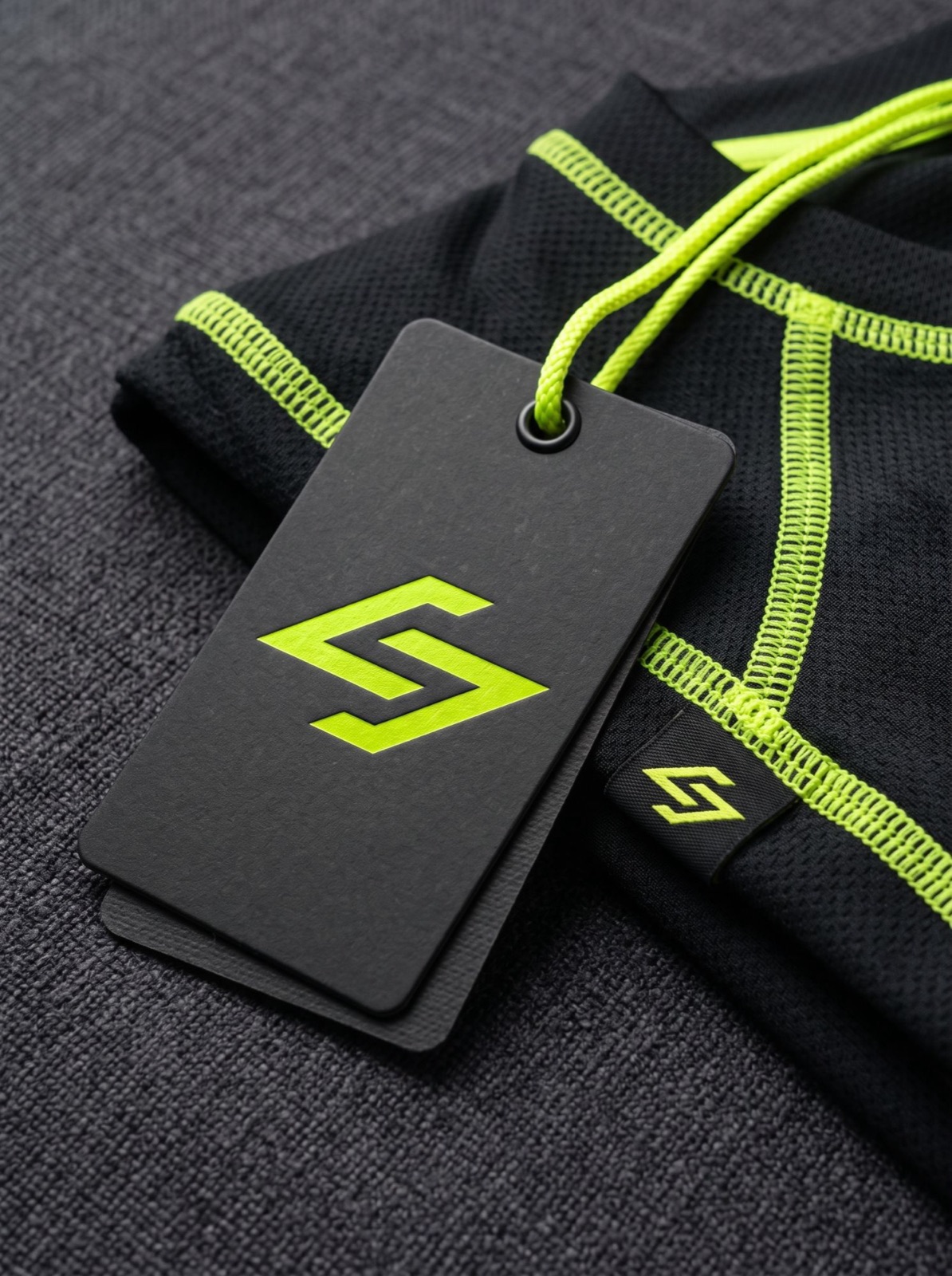 A black hang tag with a lime mark on a training shirt with lime seams