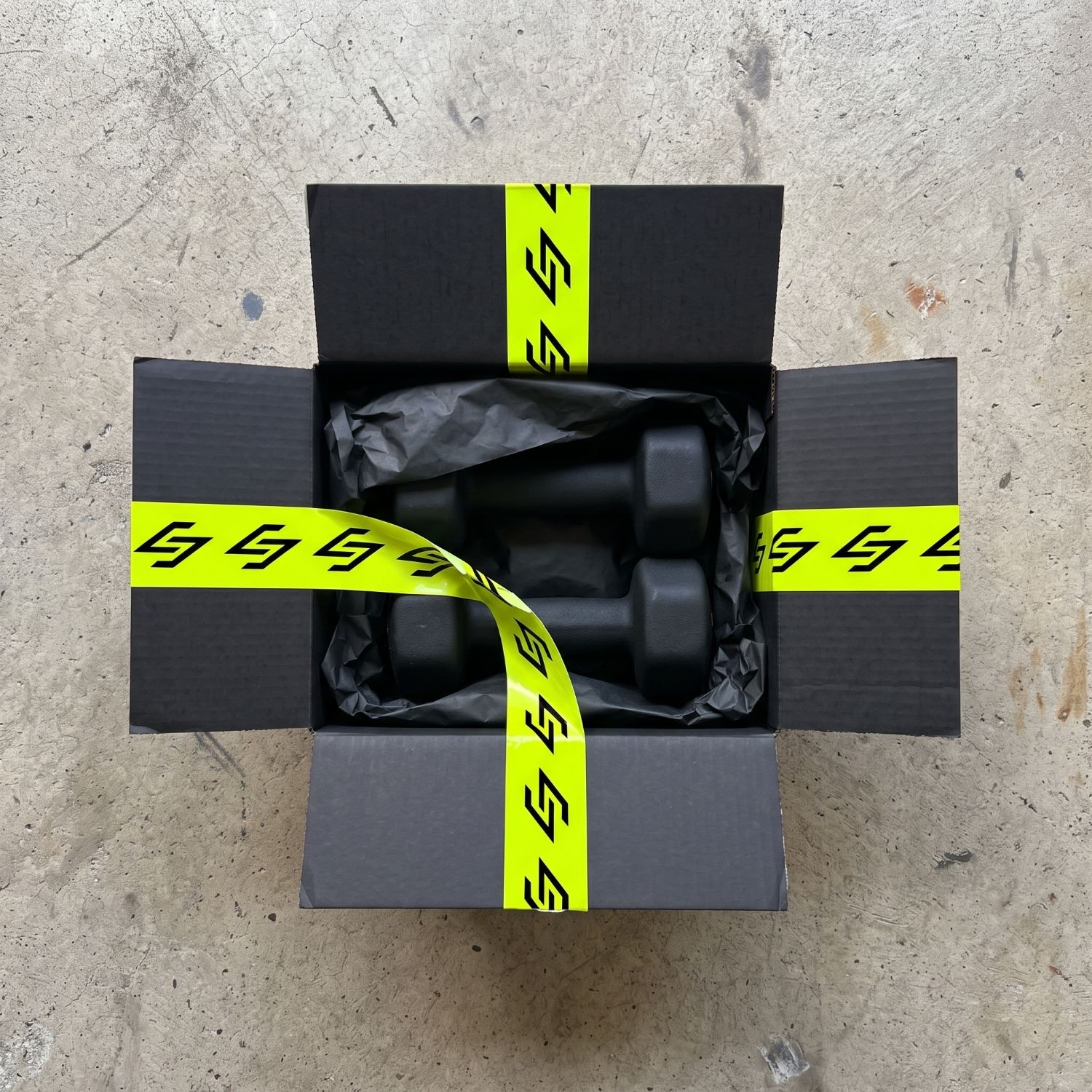 An open shipping box sealed with lime tape printed with the mark