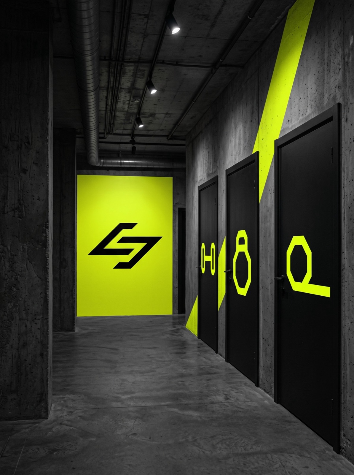 A concrete gym corridor with zone icons on black doors